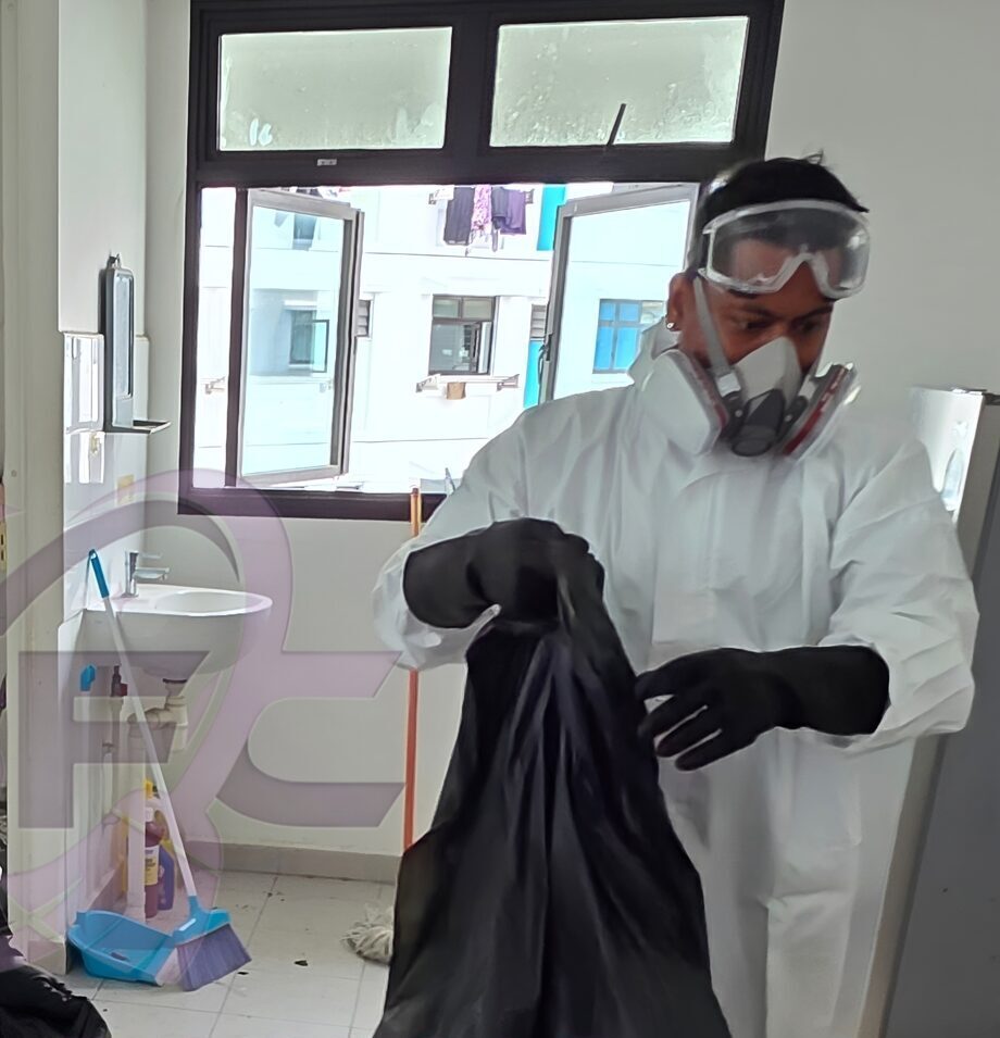 An SFC technician in a full protective coverall, respirator and goggles bagging waste on a Singapore job